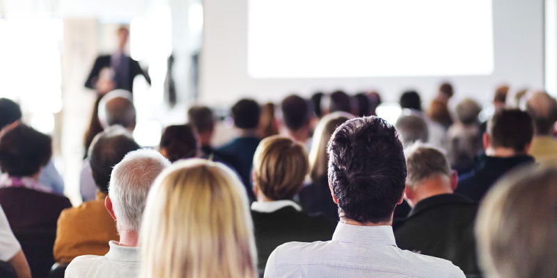 Publik sedd bakifrån under en presentation i en konferenslokal